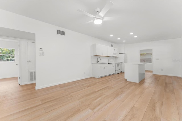 unfurnished living room with sink, ceiling fan, and light hardwood / wood-style flooring