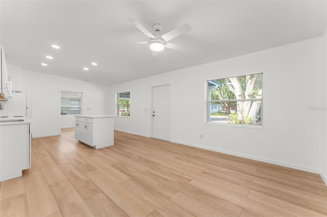 unfurnished living room featuring ceiling fan, plenty of natural light, and light wood-type flooring