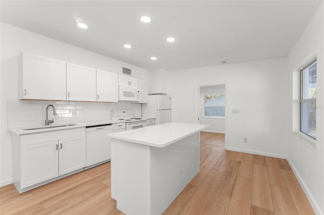 kitchen featuring sink, white appliances, a center island, light hardwood / wood-style floors, and white cabinets