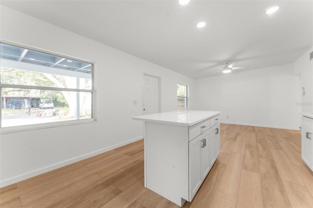 kitchen featuring white cabinetry, light wood-type flooring, ceiling fan, and a kitchen island