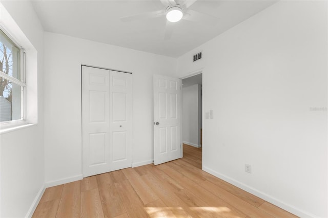 unfurnished bedroom featuring ceiling fan, light wood-type flooring, and a closet