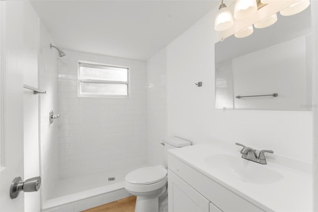 bathroom featuring vanity, a tile shower, and toilet