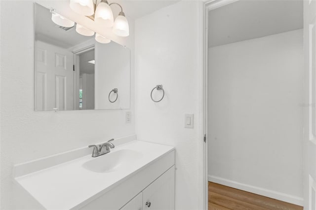 bathroom with vanity, wood-type flooring, and an inviting chandelier