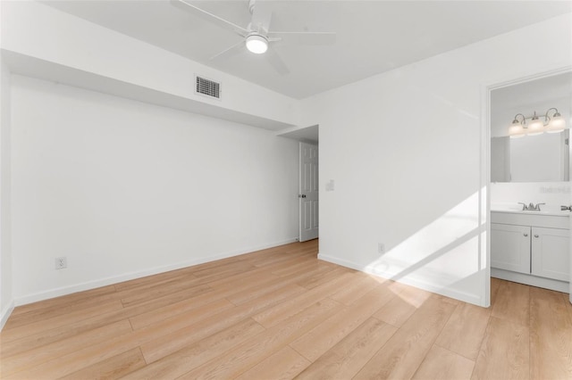 empty room with sink, ceiling fan, and light wood-type flooring