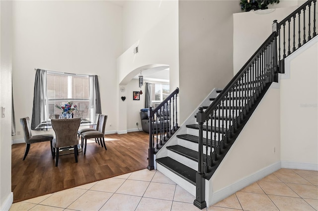 staircase with tile patterned floors and a high ceiling