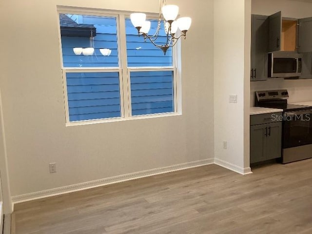 unfurnished dining area with a notable chandelier and light wood-type flooring