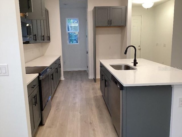 kitchen featuring sink, light hardwood / wood-style flooring, stainless steel dishwasher, range with electric cooktop, and a kitchen island with sink