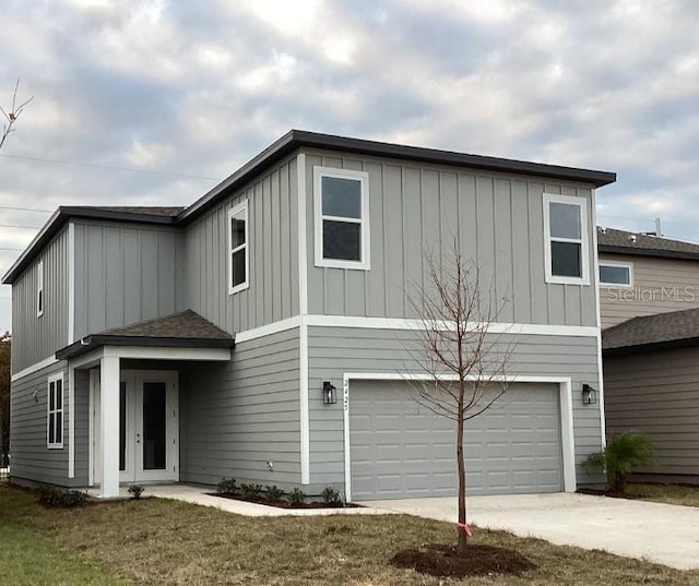 view of property with a garage, french doors, and a front lawn