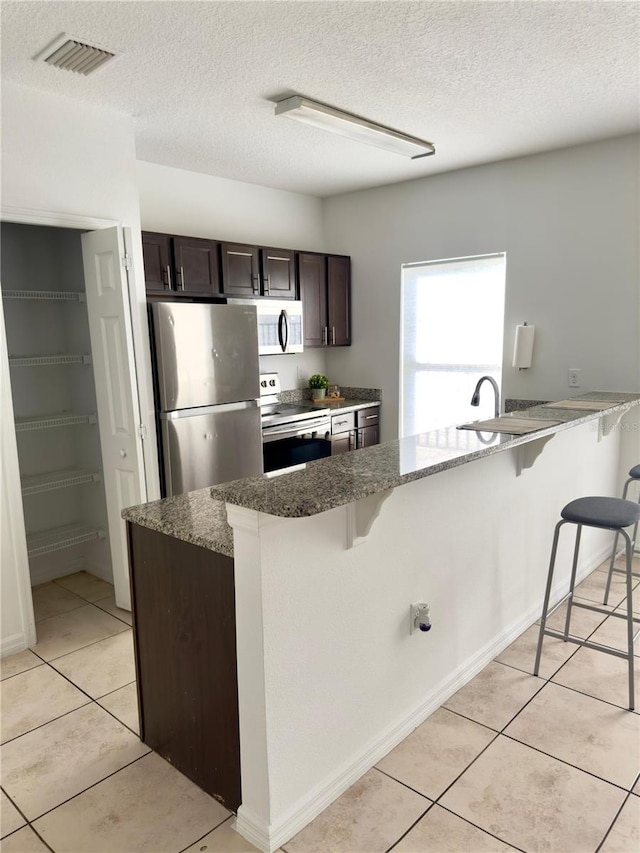 kitchen with a kitchen bar, light tile patterned flooring, and appliances with stainless steel finishes