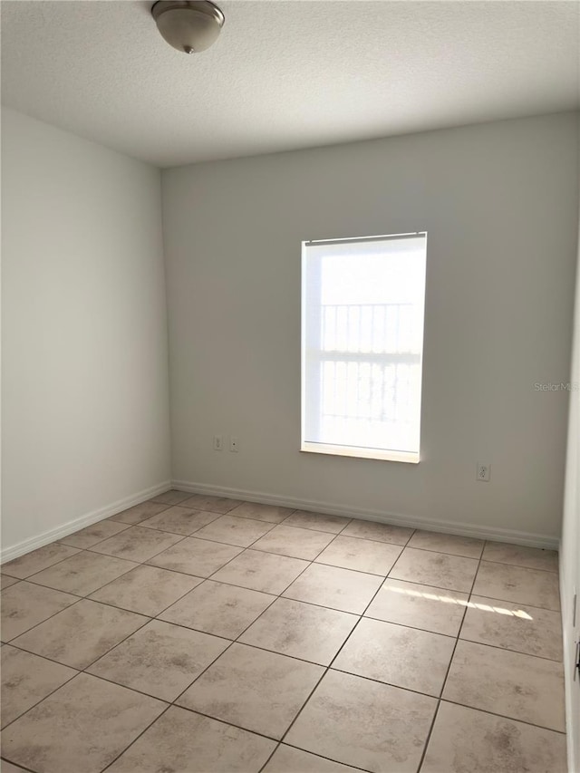 tiled empty room featuring a textured ceiling