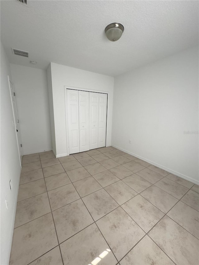 unfurnished bedroom featuring light tile patterned floors, a closet, and a textured ceiling