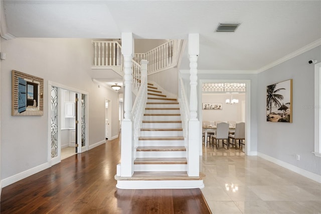 stairs featuring an inviting chandelier and ornamental molding