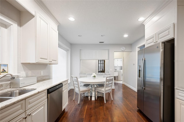 kitchen with sink, dark wood-type flooring, appliances with stainless steel finishes, light stone counters, and white cabinets