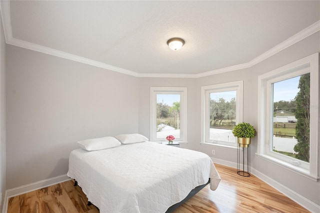 bedroom with ornamental molding and light hardwood / wood-style floors