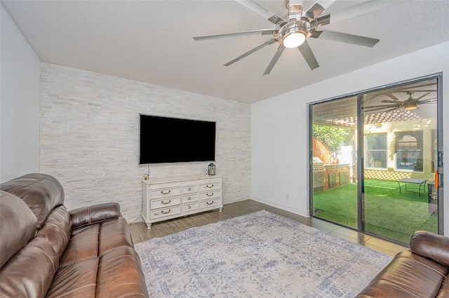 living room with hardwood / wood-style flooring, ceiling fan, and a textured ceiling