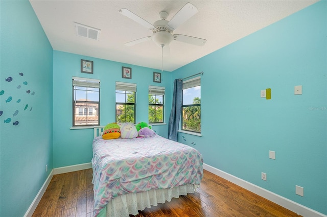 bedroom with multiple windows, dark wood-type flooring, and ceiling fan