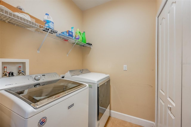 clothes washing area featuring light tile patterned floors and washer and clothes dryer