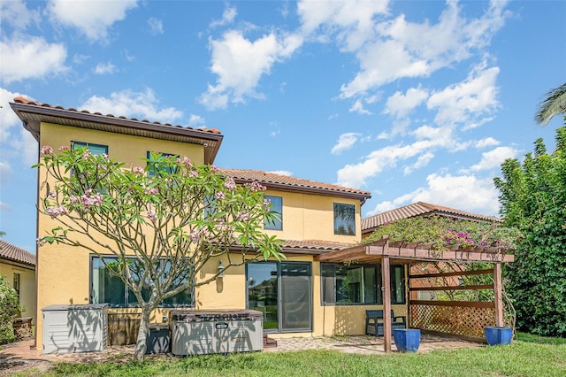 rear view of property featuring a hot tub, a yard, and a pergola