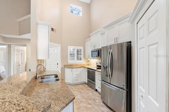 kitchen featuring white cabinetry, sink, stainless steel appliances, and a high ceiling