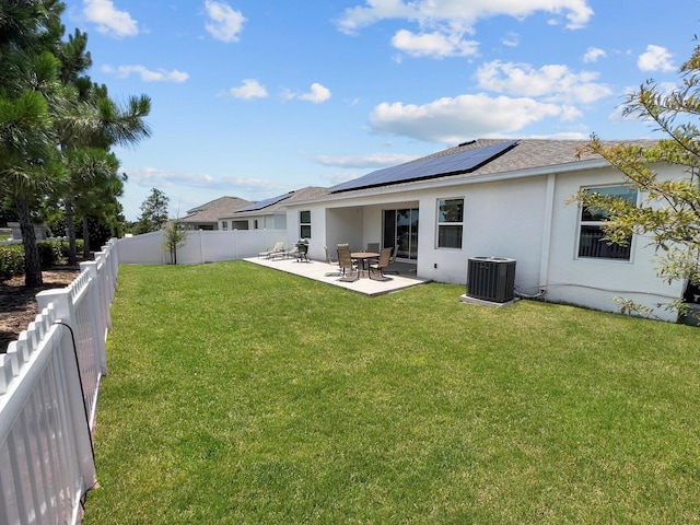 back of house featuring cooling unit, a lawn, a patio, and solar panels