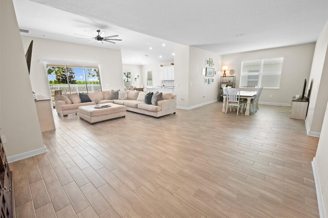 living room with ceiling fan, light hardwood / wood-style floors, and a textured ceiling