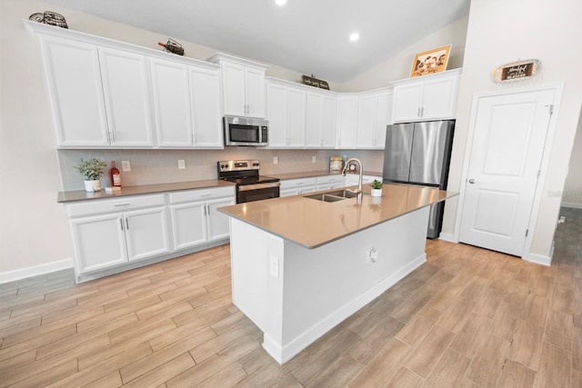 kitchen with sink, light wood-type flooring, white cabinets, stainless steel appliances, and backsplash