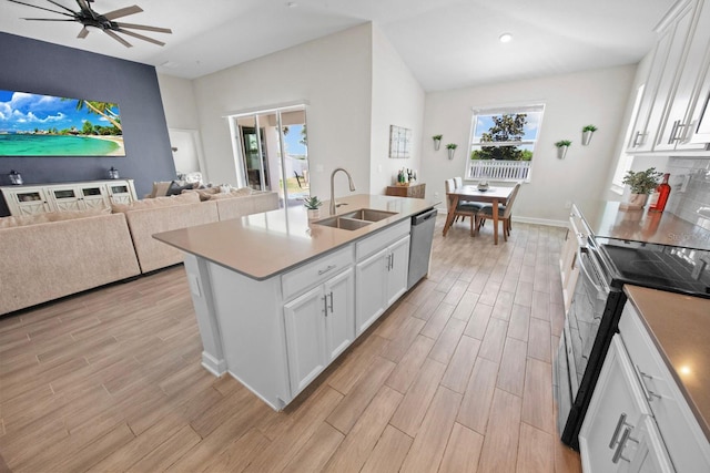 kitchen featuring electric range oven, sink, white cabinets, stainless steel dishwasher, and a center island with sink