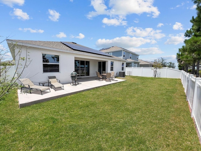 back of house featuring a yard, a patio, and solar panels