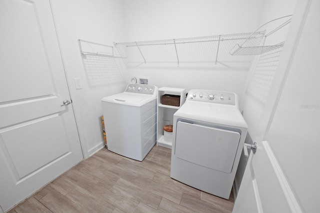 laundry room featuring washing machine and dryer and light hardwood / wood-style floors