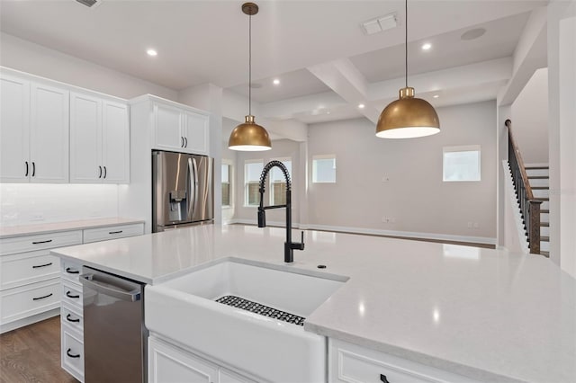 kitchen with stainless steel appliances, white cabinetry, hanging light fixtures, and sink