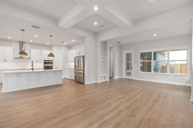 unfurnished living room featuring beamed ceiling, sink, and light wood-type flooring