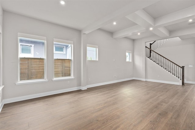 unfurnished living room featuring a healthy amount of sunlight, beam ceiling, and light wood-type flooring