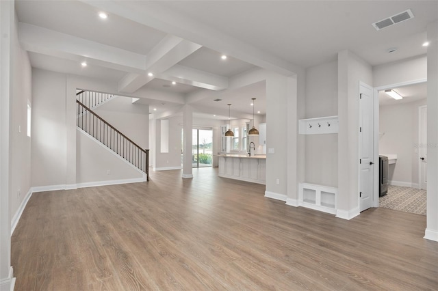 unfurnished living room featuring beamed ceiling, wood-type flooring, and sink