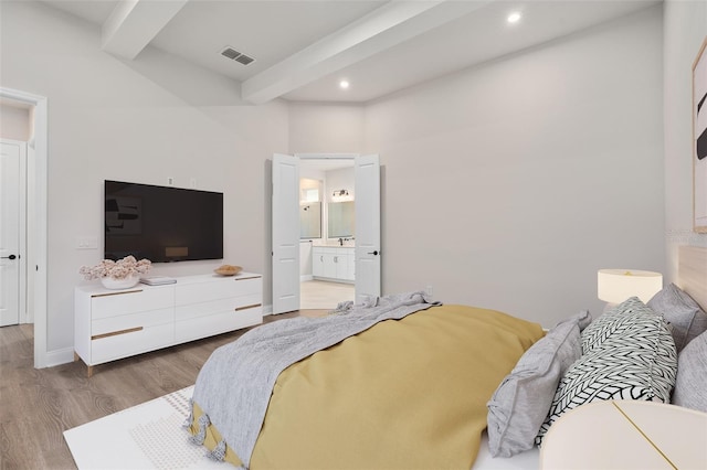 bedroom with beamed ceiling, ensuite bathroom, and wood-type flooring