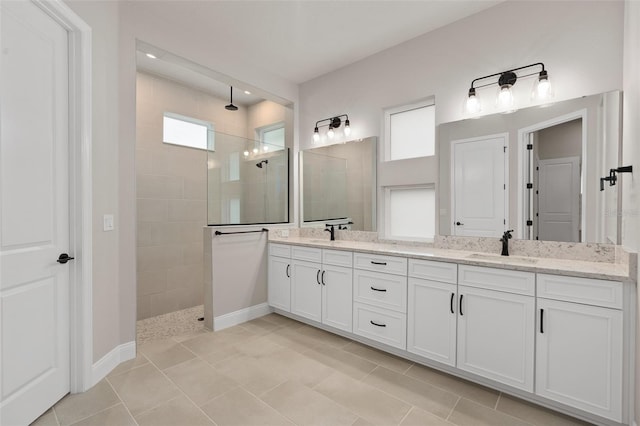 bathroom with tile patterned flooring, vanity, plenty of natural light, and tiled shower