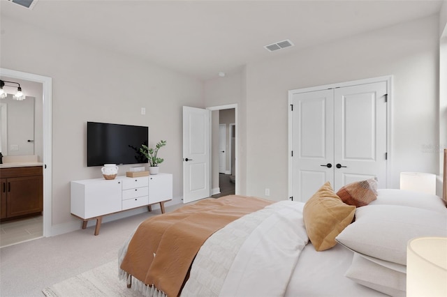 bedroom featuring ensuite bathroom, light carpet, and a closet