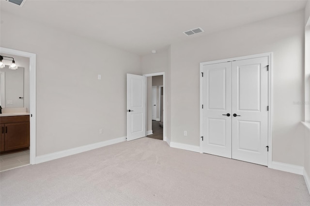 unfurnished bedroom featuring light carpet, connected bathroom, and a closet