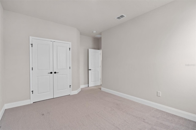 unfurnished bedroom with light colored carpet and a closet