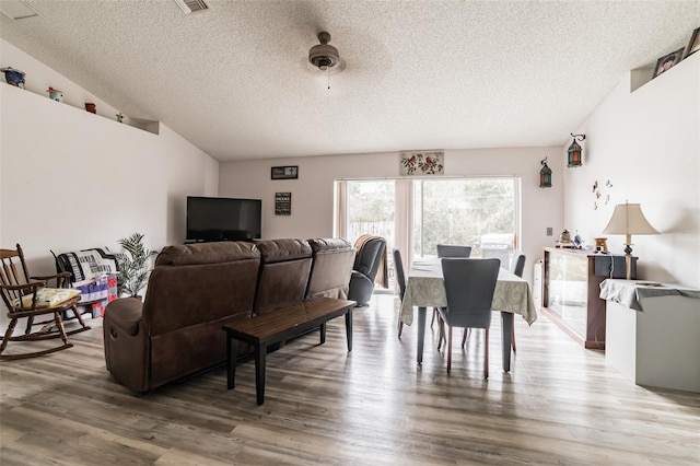 dining space with lofted ceiling, hardwood / wood-style floors, and a textured ceiling