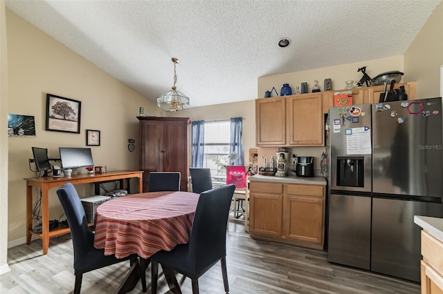 dining room featuring hardwood / wood-style flooring, vaulted ceiling, and a textured ceiling