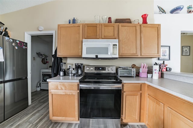 kitchen featuring stainless steel appliances, wood-type flooring, a textured ceiling, washer / clothes dryer, and light brown cabinets