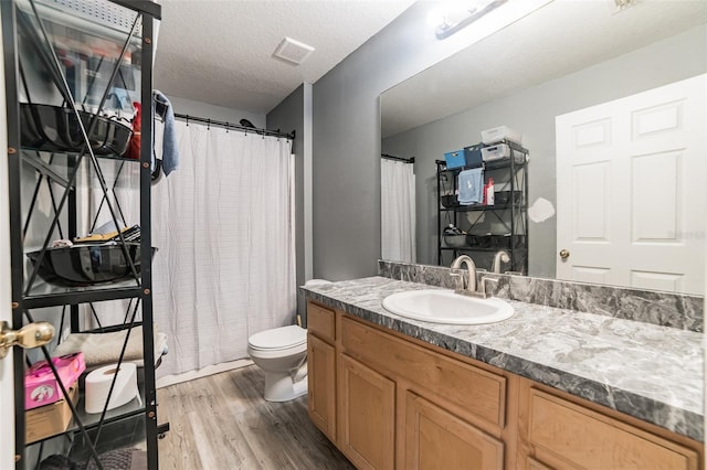 bathroom with vanity, hardwood / wood-style floors, toilet, and a textured ceiling