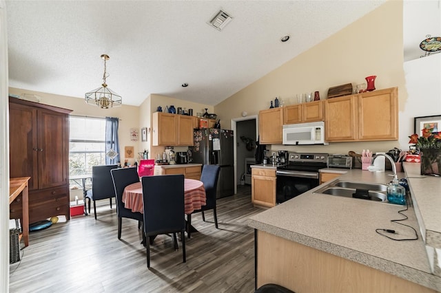 kitchen with black refrigerator, decorative light fixtures, lofted ceiling, sink, and electric stove