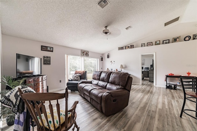 living room with lofted ceiling, a textured ceiling, and light hardwood / wood-style flooring