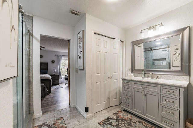 bathroom featuring vanity, an enclosed shower, and a textured ceiling