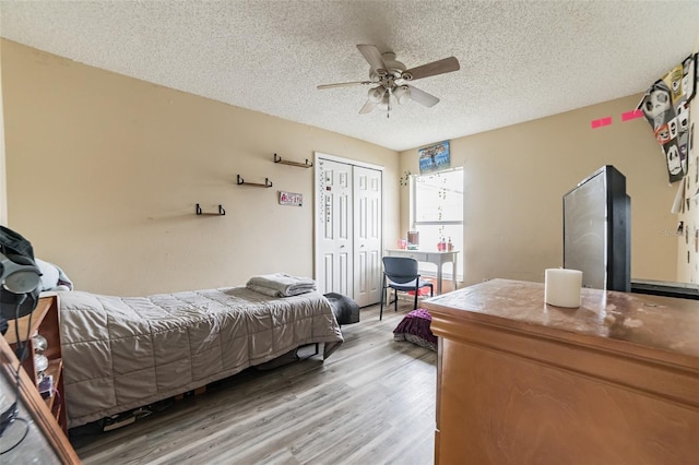 bedroom with ceiling fan, light hardwood / wood-style floors, a closet, and a textured ceiling