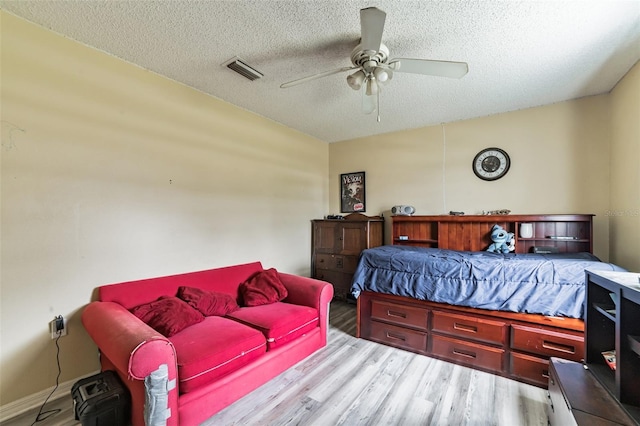 bedroom with a textured ceiling, light hardwood / wood-style flooring, and ceiling fan