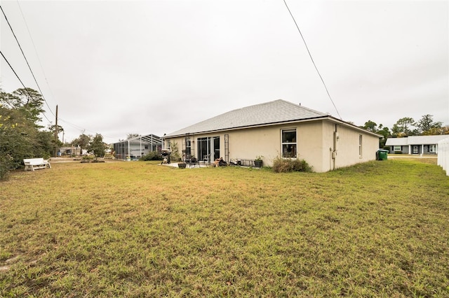 back of property featuring a lawn and glass enclosure