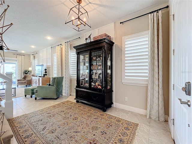 sitting room with an inviting chandelier, a textured ceiling, and light tile patterned floors