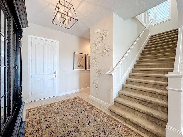 tiled foyer with an inviting chandelier and a textured ceiling